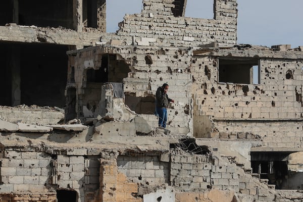 A Syrian man speaks on his mobile phone as stands on the stairs of a damaged building in the town of Harasta, east of Damascus, Syria, Thursday, Dec. 12, 2024. (AP Photo/Omar Sanadiki)