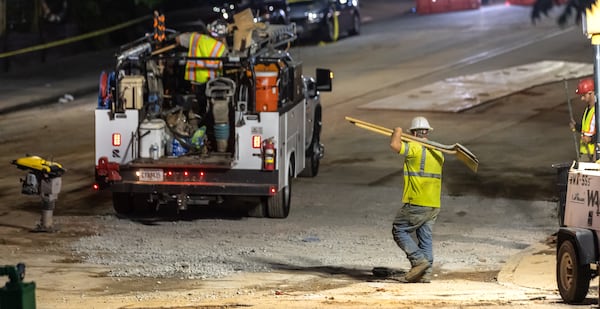 Workers continued to put the finishing touches on the filled in water main hole Wednesday morning, June 5, 2024 following the city’s announcement that water had been restored following the break on West Peachtree Street and 11th Street. The city said the system was being brought back online slowly to “allow system pressures to build.” (John Spink/AJC)