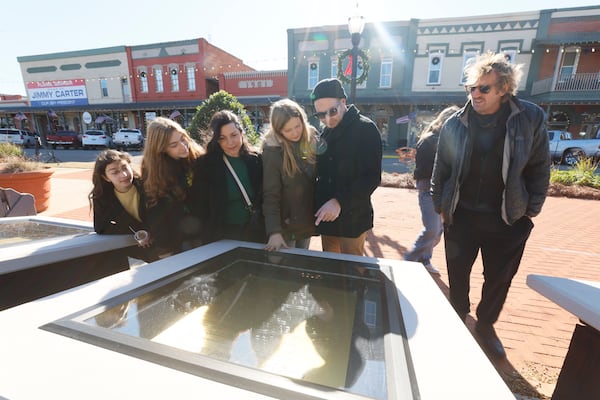 John Chuldenko (second from the right) and his family and friends gathered in downtown Plains on Friday to view the U.S. Constitution display. They had traveled from Los Angeles to pay their respects to the former president. (Miguel Martinez/AJC)