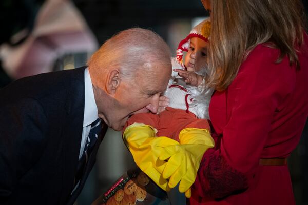 President Joe Biden joking bites the leg of a baby, as he and first lady Jill Biden host local area students, military-connected children, and neighborhood families for trick-or-treating, ahead of Halloween on Thursday, at the South Lawn of the White House in Washington Wednesday, Oct. 30, 2024. (AP Photo/Ben Curtis)