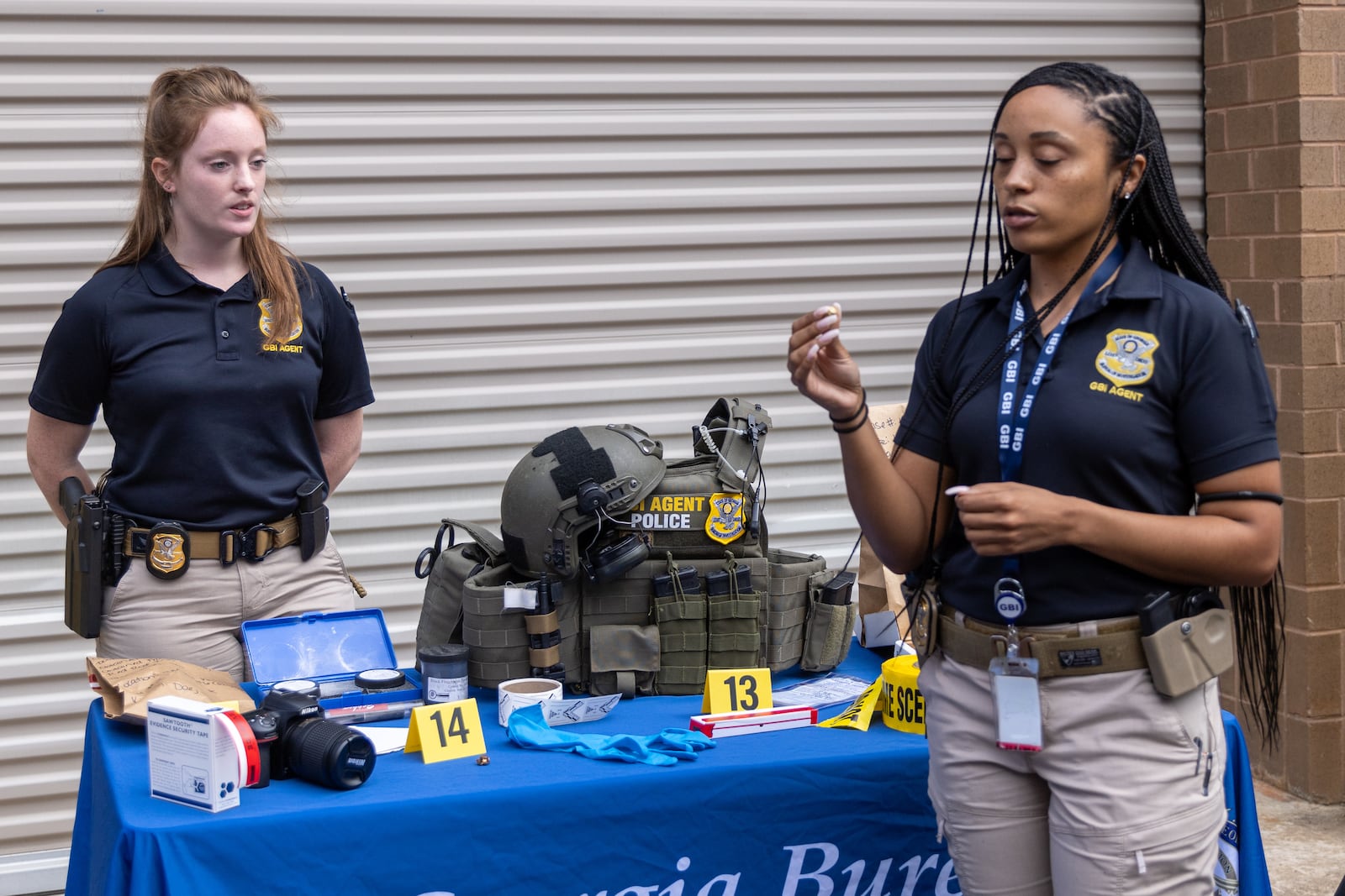 GBI special agent Ashley Brown (right) holds a shell casing while GBI special agent Cassidy Patterson looks on during a media day event at their Decatur headquarters Friday, August 16, 2022.