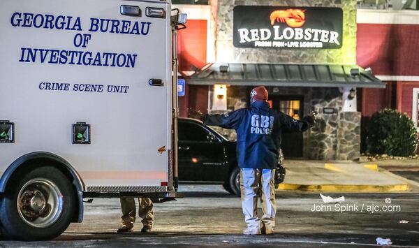 GBI agents process the scene Tuesday morning after an off-duty Clarkston officer was involved in a shootout with robbery suspects in the parking lot of a Red Lobster on Candler Road. JOHN SPINK / JSPINK@AJC.COM