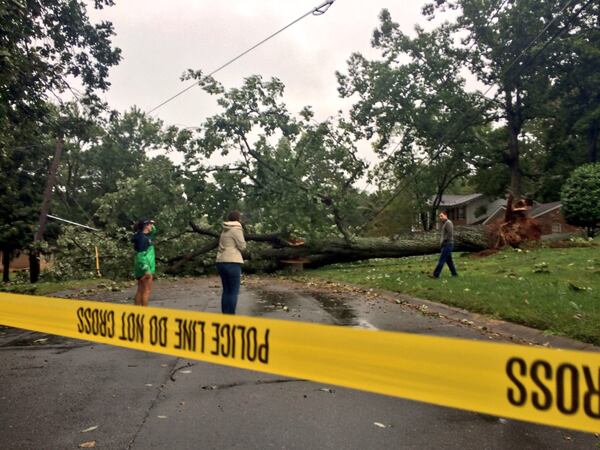 Residents in the area of Vernon Oaks Drive in Dunwoody scope out a fallen tree, Tuesday, September 12, 2017, that cut power lines and snapped utility poles following high winds and heavy rain from Tropical Storm Irma. J. SCOTT TRUBEY/STRUBEY@AJC.COM