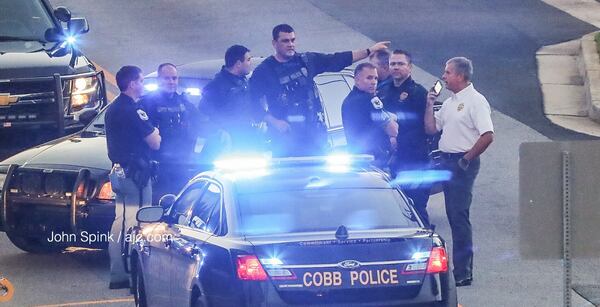 Cobb County police investigators gather Friday morning on the scene of a shooting at an Akers Mill Road apartment complex. JOHN SPINK / JSPINK@AJC.COM