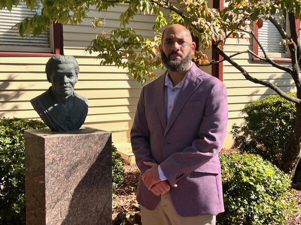 Corey Rogers stands next to a bust of Lucy Craft Laney in the courtyard of the museum bearing her name. (Charmain Brackett/Augusta Good News)