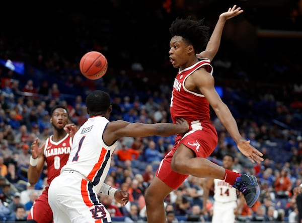 Alabama's Collin Sexton, right, makes a no-look pass to teammate Donta Hall, left, around Auburn's Jared Harper, center, during the second half in an NCAA college basketball quarterfinal game at the Southeastern Conference tournament Friday, March 9, 2018, in St. Louis. Alabama won 81-63. (AP Photo/Jeff Roberson)