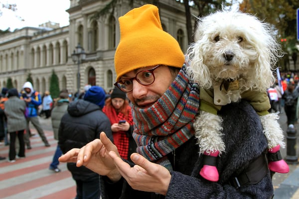 A protester with his dog walks in a street during a rally to demand new parliamentary elections in the country, near the Parliament's building in Tbilisi, Georgia, on Monday, Nov. 25, 2024. (AP Photo/Shakh Aivazov)