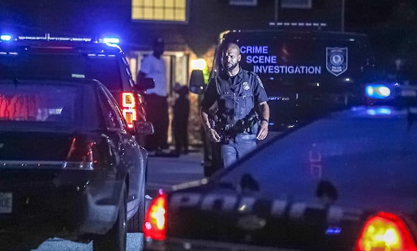 A DeKalb County police officer walks away from a home on Young Knoll in the Redan area, where a shooting investigation was underway Monday morning.