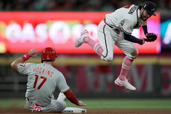 Braves shortstop Dansby Swanson (right) hops over Philadelphia Phillies' Rhys Hoskins (17) after completing a double play during the seventh inning Sunday, May 9, 2021, at Truist Park in Atlanta. Phillies' Odubel Herrera was out at first base. (Ben Margot/AP)