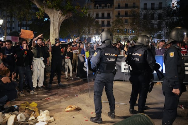 Demonstrators shout as riot police watches duringa protest organized by social and civic groups, denouncing the handling of recent flooding under the slogan "Mazón, Resign," aimed at the president of the regional government Carlos Mazon, in Valencia, Spain, Saturday, Nov. 9, 2024. (AP Photo/Emilio Morenatti)