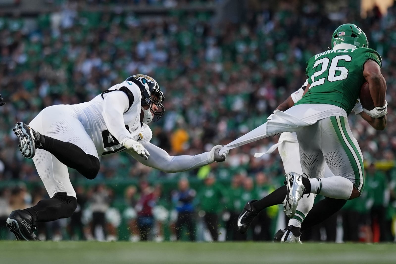 Jacksonville Jaguars defensive end Arik Armstead (91) holds on to Philadelphia Eagles running back Saquon Barkley (26) during the first half of an NFL football game Sunday, Nov. 3, 2024, in Philadelphia. (AP Photo/Matt Slocum)