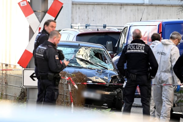 Police officers stand next to a damaged vehicle in the city center of Mannheim, Germany, Monday March 3, 2025, following an incident in which one person was killed and others injured when a car rammed into a crowd, German police said. (Boris Roessler/dpa via AP)