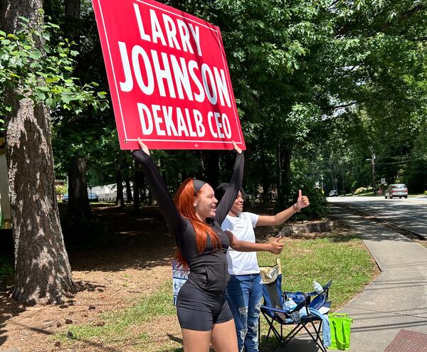 Nylah McDowell and Iona Atwaters, 19-year-old volunteers for DeKalb County CEO candidate Larry Johnson, encourage passing motorists on Lavista Road to cast their ballots in Tuesday's general primary.