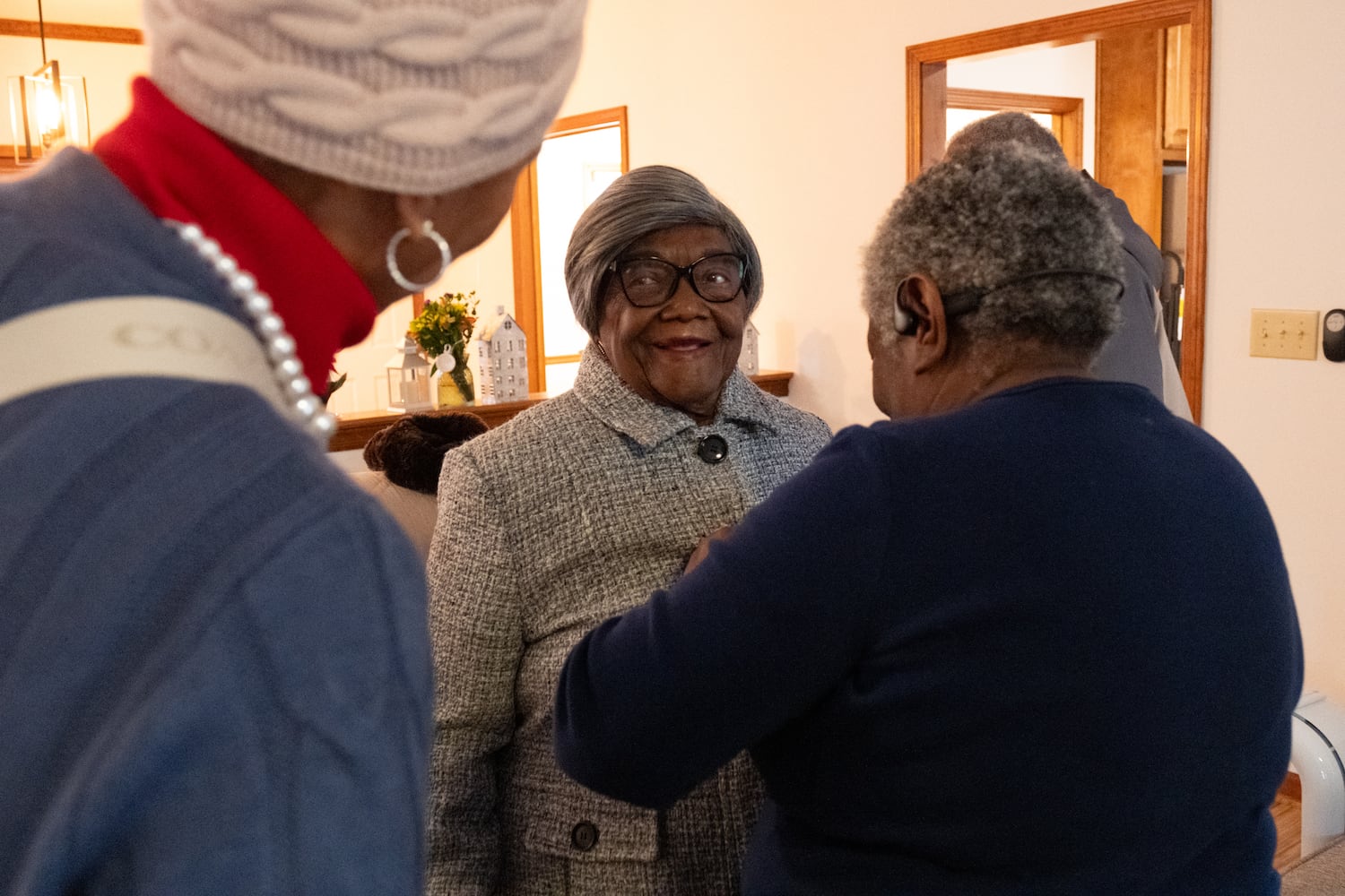 Lillie Mae Hightower smiles as her daughter Carolyn Mitchell buttons up her coat before heading outside to see a parade of DeKalb and Henry County Sheriff vehicles parade by in celebration of her 102nd birthday in Stockbridge on Friday, Dec. 27, 2024.   Ben Gray for the Atlanta Journal-Constitution