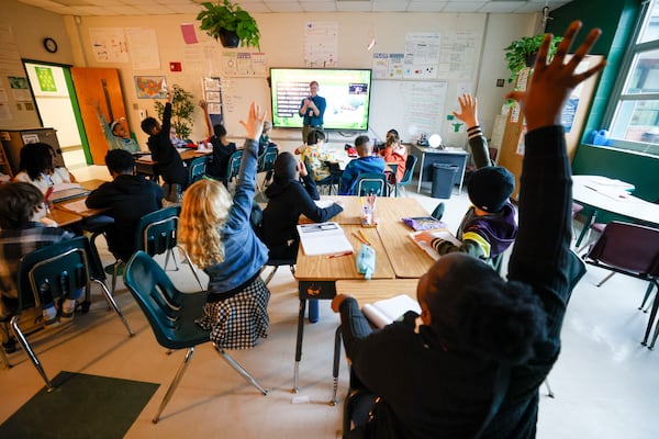 Fourth grade students raise their hands to answer a question during a reading class at Parkside Elementary School on Feb. 6. Atlanta Public Schools extended the school day for elementary school students by 30 minutes and implemented a summer recovery program when students returned to in-person classes in the aftermath of the COVID-19 pandemic. Officials think those measures could have contributed to recent score increases on national math and reading tests. Miguel Martinez/AJC