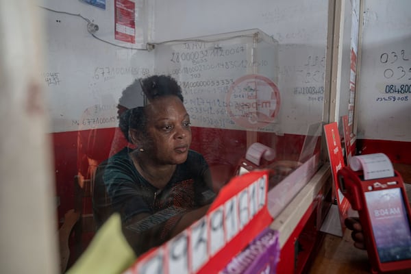 Lucie Lusamba uses a currency exchange office in downtown Goma, Democratic Republic of Congo, Thursday, Feb. 27, 2025, one month after Rwanda-backed M23 rebels captured the city. (AP Photo/Moses Sawasawa)