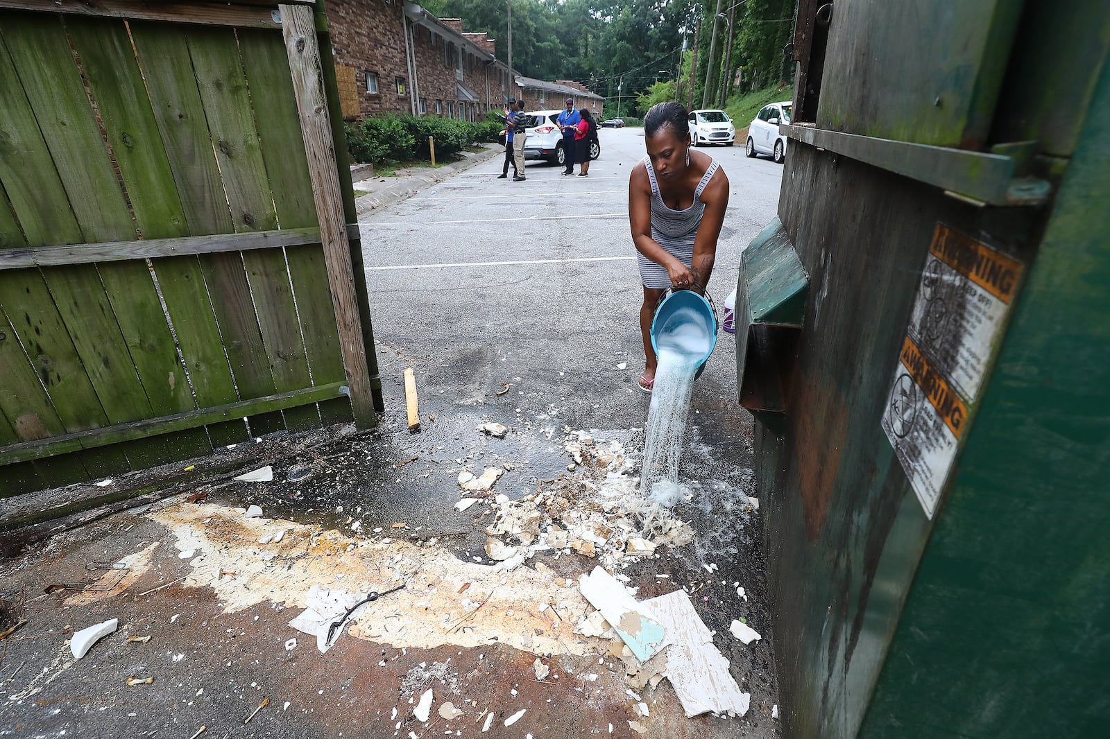 Resident Danielle Russell pours bleach over raw sewage that spilled from a discarded toilet left in the parking lot near her Pavilion Place apartment in August 2022. That day, Atlanta officials conducted a complexwide inspection of conditions, which led to a prosecution of its owner on dozens of code enforcement violations. (Curtis.Compton/Curtis Compton@ajc.com)