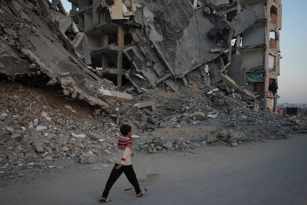 A Palestinian boy walks past destroyed building at a neighbourhood in Khan Younis, Gaza Strip, Sunday, Dec. 1, 2024. (AP Photo/Abdel Kareem Hana)