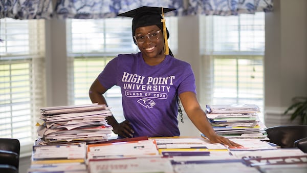 Liberty County High School graduate Madison Crowell poses with some of the college scholarship offers laid out on her dining room table on Wednesday, May 29, 2024 in Hinesville, Georgia. Crowell plans on attending High Point University in North Carolina. (AJC Photo/Stephen B. Morton)