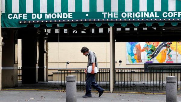 A man walks past a closed Cafe Du Monde, in the French Quarter of New Orleans, normally bustling with tourists, but now nearly completely deserted due to the new coronavirus pandemic, Friday, March 27, 2020. (AP Photo/Gerald Herbert)