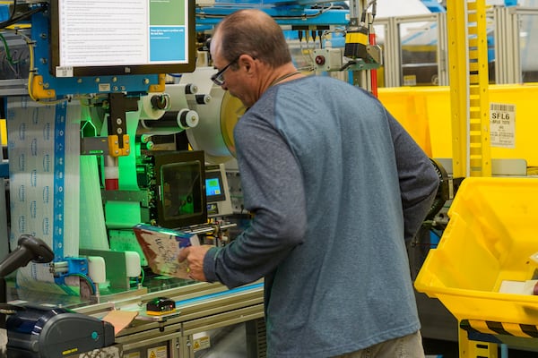 FILE - An employee uses an automated packaging machine to create a made-to-measure bag for a book at Amazon OXR1 fulfillment center in Oxnard, Calif., on Aug. 21, 2024. (AP Photo/Damian Dovarganes, File)