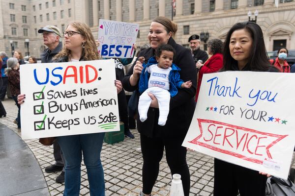 FILE - United States Agency for International Development (USAID) supporters hold banners as USAID workers retrieve their personal belongings from the USAID's headquarters in Washington, Feb. 27, 2025. (AP Photo/Manuel Balce Ceneta, file)