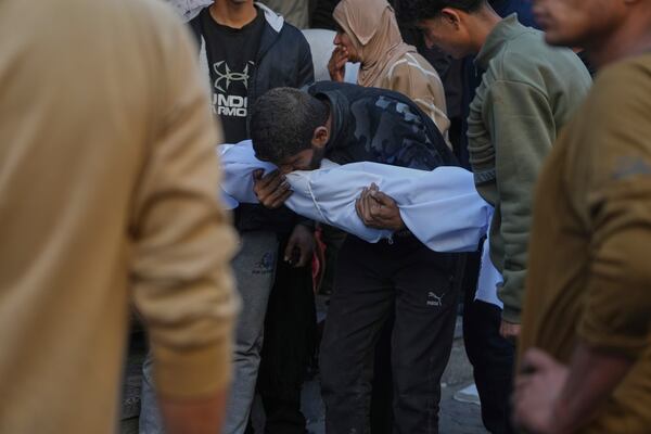 A man carries a covered body following overnight Israeli airstrikes across the Gaza Strip, at the Al-Ahli hospital in Gaza City, Tuesday, March 18, 2025. (AP Photo/Jehad Alshrafi)