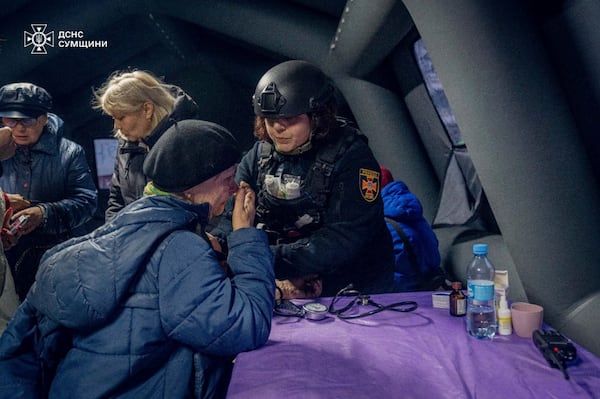 In this photo provided by the Ukrainian Emergency Service, a psychologist works with residents of houses which were hit by a Russian attack in Sumy, Ukraine, Tuesday, March 25, 2025. (Ukrainian Emergency Service via AP)