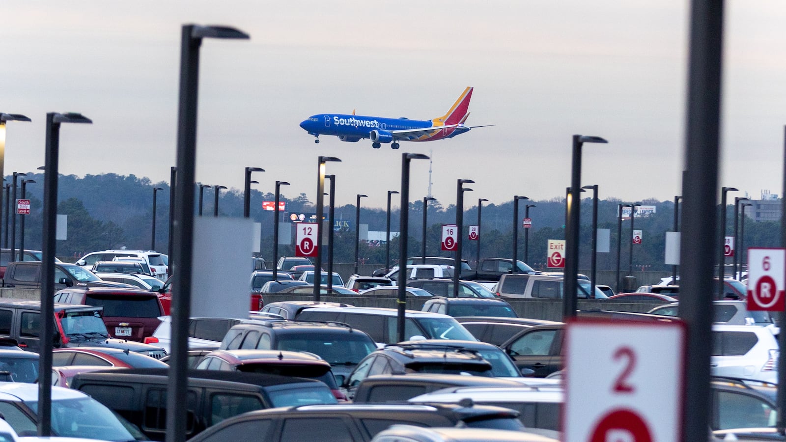 A Southwest Airlines plane lands near a full parking lot at Hartsfield-Jackson Atlanta International Airport on Friday, December 22, 2023. (Steve Schaefer/steve.schaefer@ajc.com)