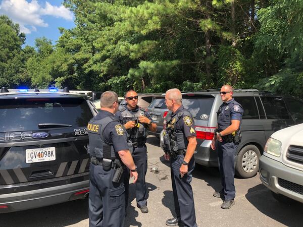 Marietta police officers gathered in the Six Flags at White Water parking lot Thursday to rescue a dog left in a parked car. (Credit: Marietta Police Deparment)