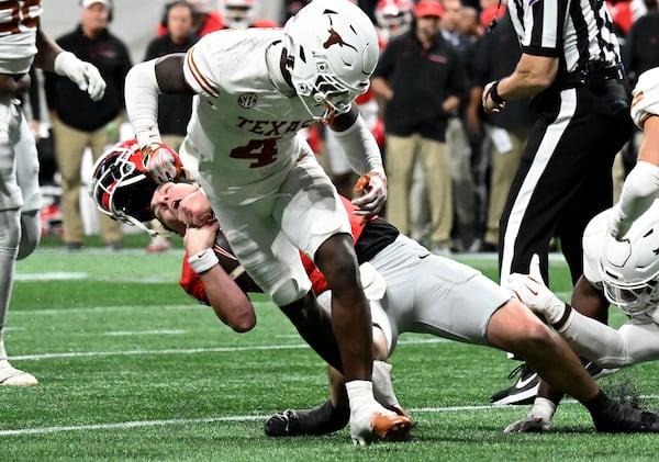 Georgia quarterback Gunner Stockton (14) gets hit by Texas defensive back Andrew Mukuba (4) in overtime during the SEC Championship football game at the Mercedes-Benz Stadium, Saturday, December 7, 2024, in Atlanta. Georgia won 22-19 over Texas in overtime. (Hyosub Shin / AJC)