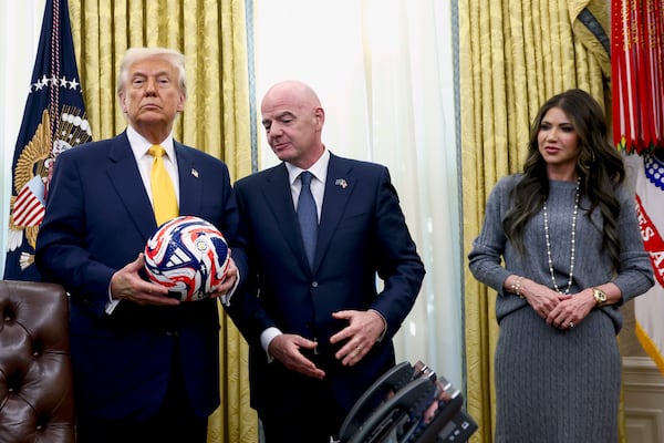 President Donald Trump, from left, holds the new FIFA Club World Cup official ball as FIFA President Gianni Infantino and Homeland Security Secretary Kristi Noem watch in the Oval Office of the White House in Washington, Friday, March 7, 2025. (Pool via AP)