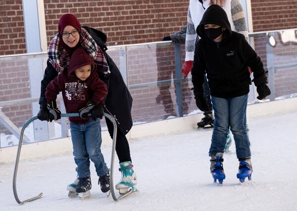 Ryma Hamek helps Luis Rodriguez, 5, make his way around the Have an Ice Day rink in downtown Sugar Hill on Saturday afternoon, December 26, 2020. (Photo: Ben Gray for The Atlanta Journal-Constitution)