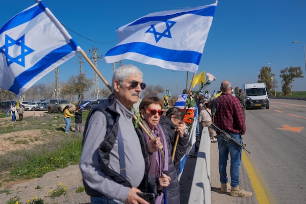 Israelis are waiting on the side of a road where the funeral convoy carrying the coffins of slain hostages Shiri Bibas and her two children, Ariel and Kfir, will pass by near Kibbutz Nir Oz, Israel, Wednesday, Feb. 26, 2025. The mother and her two children were abducted by Hamas on Oct. 7, 2023, and their remains were returned from Gaza to Israel last week as part of a ceasefire agreement with Hamas. (AP Photo/Ohad Zwigenberg)