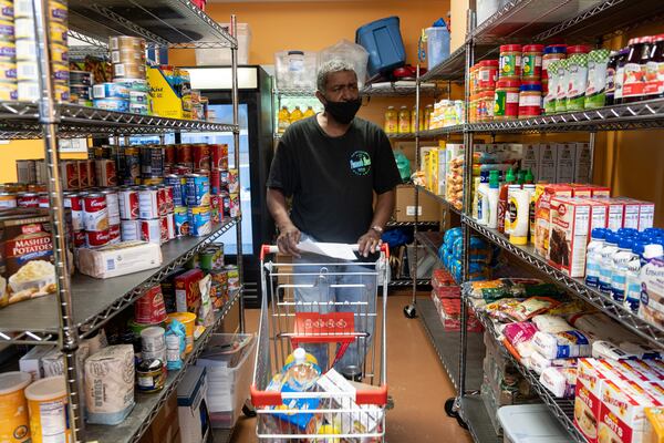 Mark Laster, a volunteer at Emmaus House in Peoplestown, selects food from the organization’s food pantry for a client. Ben Gray/ for the AJC