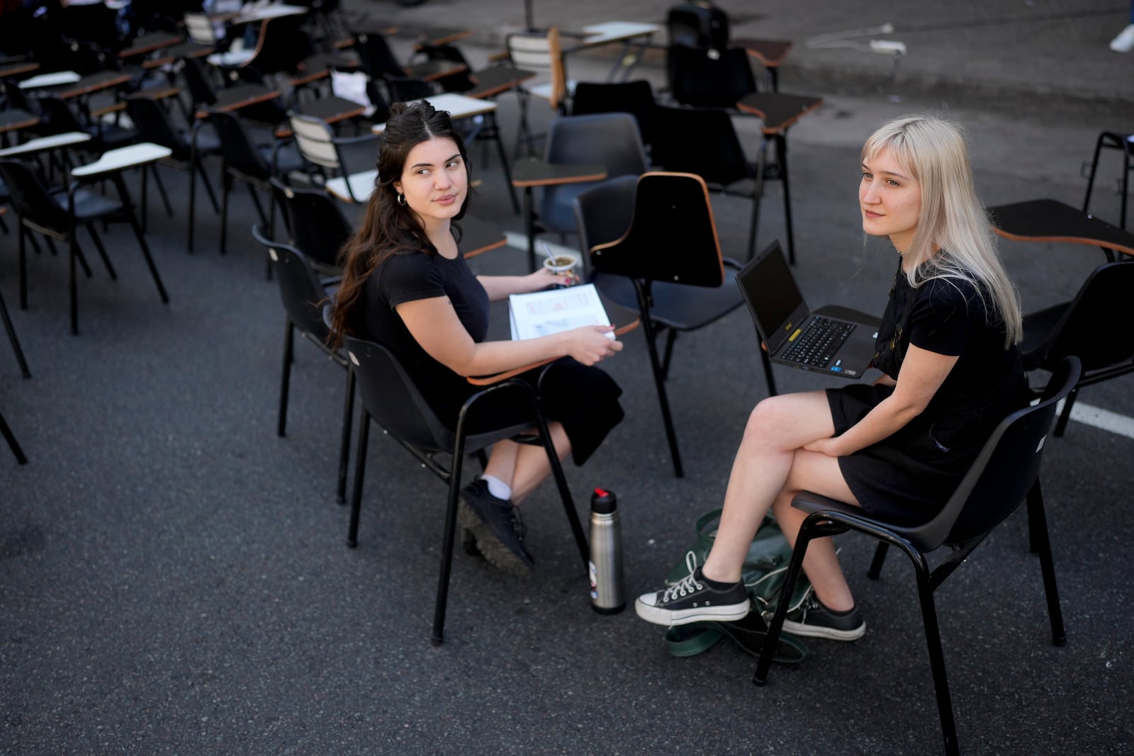 Students Antonia Goycochea, left, and Iana Ferrari sit in the middle of a street outside the Faculty of Psychology during a protest against President Javier Milei's veto of higher funding for public universities, in Buenos Aires, Argentina, Wednesday, Oct. 16, 2024. (AP Photo/Natacha Pisarenko)