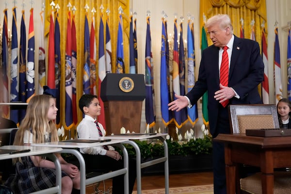 President Donald Trump, right, addresses young people before signing an executive order in the East Room of the White House in Washington, Thursday, March 20, 2025. (AP Photo/Ben Curtis)