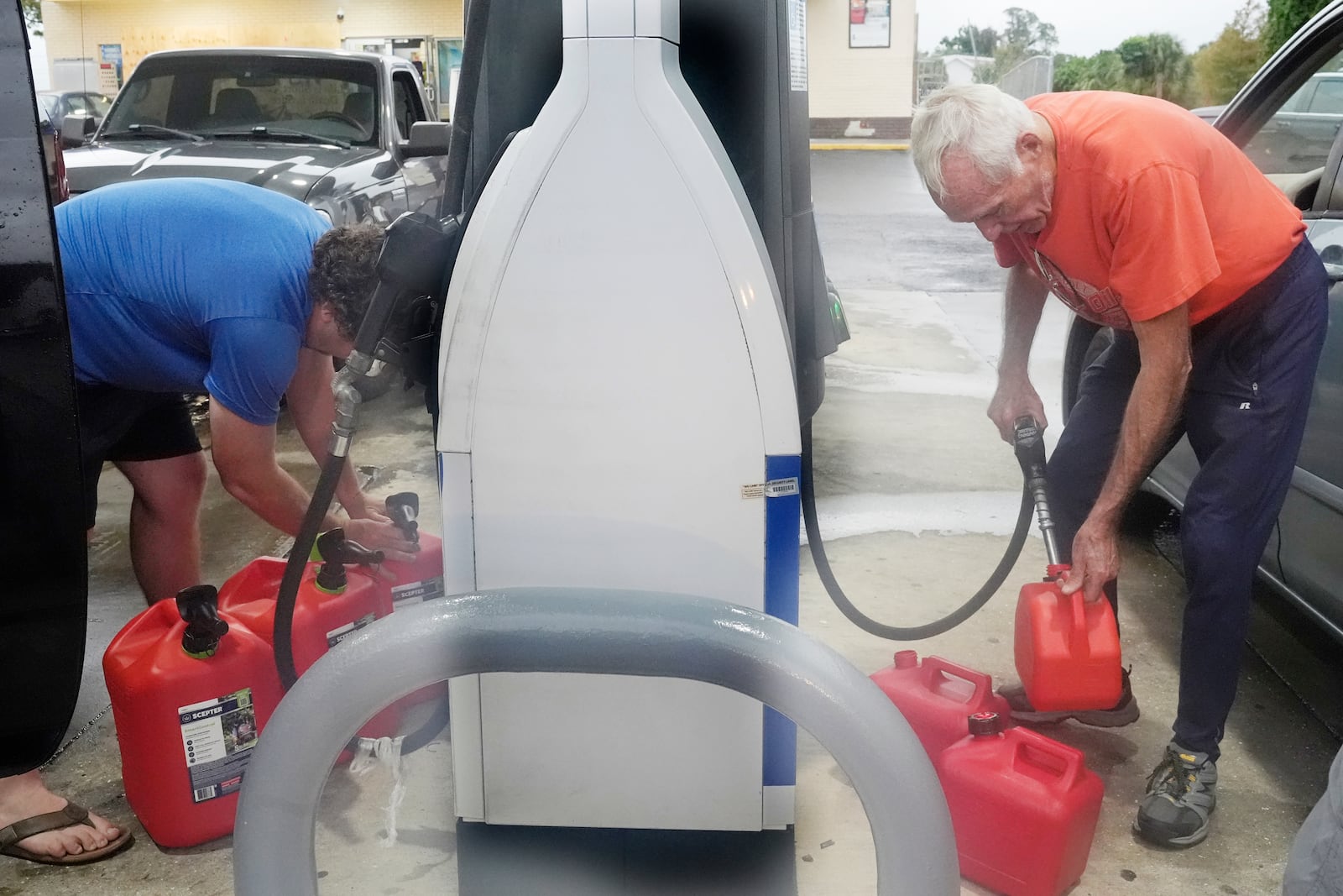 Don Hallenbeck, right, fills gas tanks as he prepares to stay in his home in advance of Hurricane Milton, Wednesday, Oct. 9, 2024, in Port Charlotte, Fla. (AP Photo/Marta Lavandier)