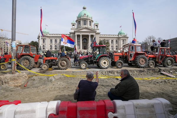 People seat in front of Serbian parliament building near students and former paramilitary fighters loyal to President Aleksandar Vucic camp outside the presidency building prior to a major anti-corruption rally in downtown Belgrade, Serbia, Saturday, March 15, 2025. (AP Photo/Darko Vojinovic)