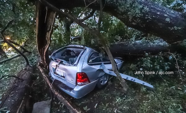 Firefighters cut free a 31-year-old woman who became trapped in a vehicle after a tree fell on it. JOHN SPINK / JSPINK@AJC.COM