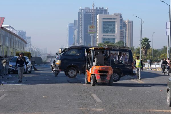 Traffic police officers remove a damaged vehicle left behind by supporters of imprisoned former Prime Minister Imran Khan's Pakistan Tehreek-e-Insaf party, when security forces launched an operation Tuesday night to disperse them, in Islamabad, Pakistan, Wednesday, Nov. 27, 2024. (AP Photo/Anjum Naveed)