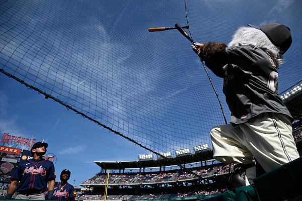 Washington Nationals' mascot Screech, right, tries to dislodge Atlanta Braves' Ozzie Albies's bat, second from bottom left, that got stuck in the netting after Albies' lost his grip on it during his at-bat in the first inning of a baseball game against the Washington Nationals, Saturday, June 8, 2024, in Washington. Braves' Austin Riley, bottom left, watches. (AP Photo/Nick Wass)