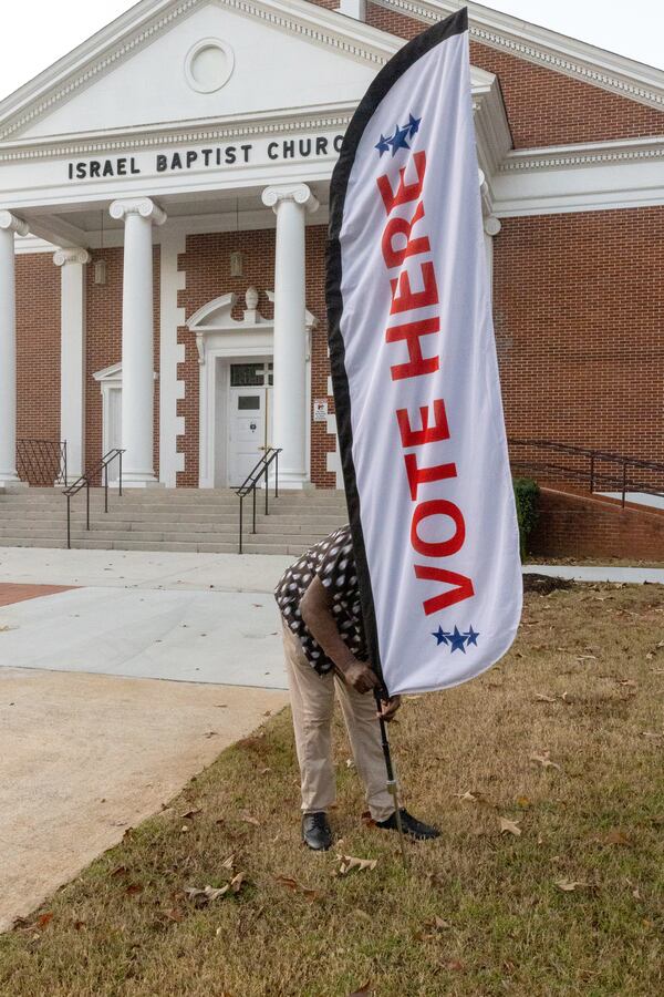 Assistant Poll Manager Jasper Perry situates the signage outside Israel Baptist Church on election day, Tuesday, Nov. 8, 2022.  (Steve Schaefer/steve.schaefer@ajc.com)