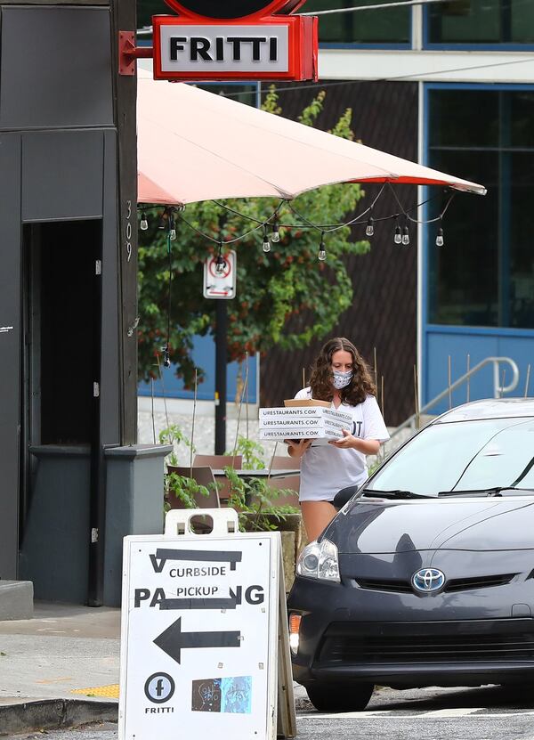 A woman uses curbside pickup for carry out pizza from Fritti on Tuesday, May 26, 2020, in Atlanta. The Inman Park restaurants Sotto Sotto and Fritti reopened to dine-in customers as soon as legally allowed, but employees of the restaurant have said chef/owner Ricardo Ullio has not put appropriate measures in place to protect them or the diners who have come flooding back. CURTIS COMPTON CCOMPTON@AJC.COM