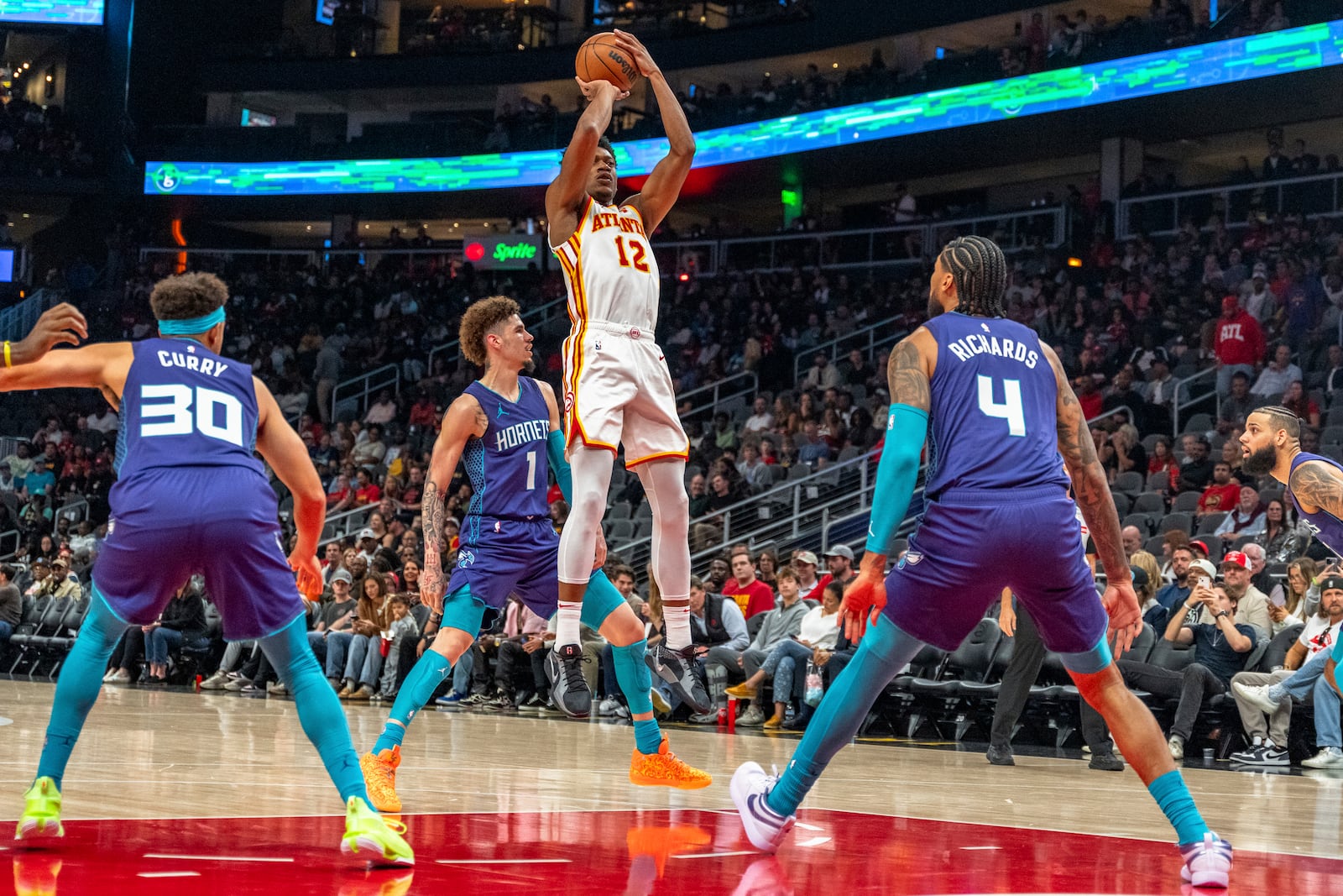 Atlanta Hawks forward De'Andre Hunter (12) goes to make a jump shot from the field while guarded by Charlotte Hornets center Nick Richards (4) during the first half of an NBA basketball game, Friday, Oct. 25, 2024, in Atlanta. (AP Photo/Jason Allen)