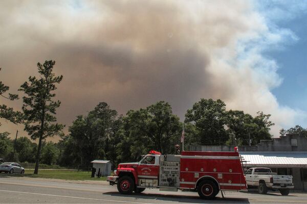 A firetruck passes as a plume of smoke rising from a wildfire burning just outside the town of St. George, Ga. (AP photo/Russ Bynum/May 8, 2017)