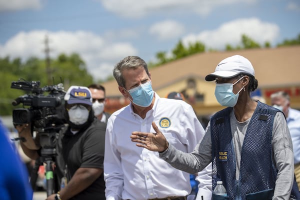 Georgia Gov. Brian Kemp receives information about a community COVID-19 testing site from Public Health District 2 Director, Dr. Pamela Logan (right), in the parking lot of La Flor de Jalisco #2 during a visit to Gainesville, Friday, May 15, 2020. ALYSSA POINTER / ALYSSA.POINTER@AJC.COM