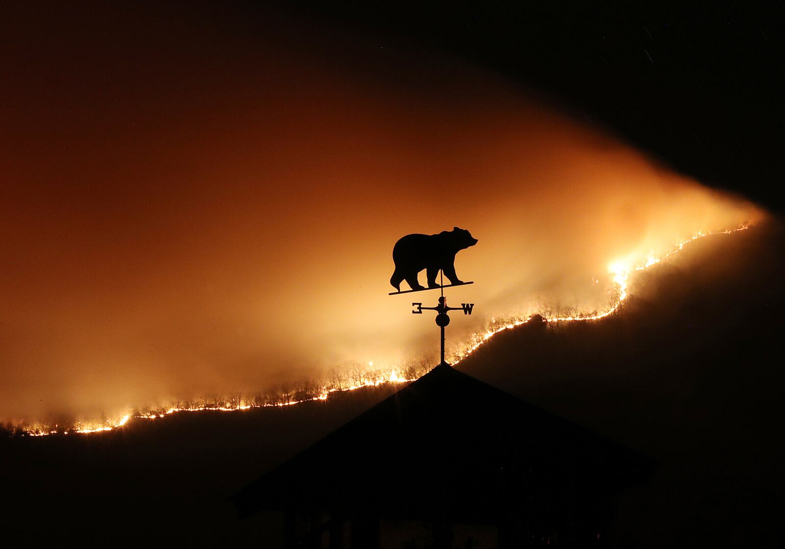 At first glance the weathervane on the top of a barn appears to be a bear fleeing the Rock Mountain Fire as it burns across the top of ridge pole above Bettyâs Creek Road where home owners are under a pre-evacuation order just north of Clayton. Thousands of acres have been burned by wildfires in the Georgia mountains from extreme drought conditions. Made with a Canon EOS 1DX Mark II camera, a 300 mm lens, 32 second, F/32, ISO 5000, and a tripod.   Curtis Compton/ccompton@ajc.com