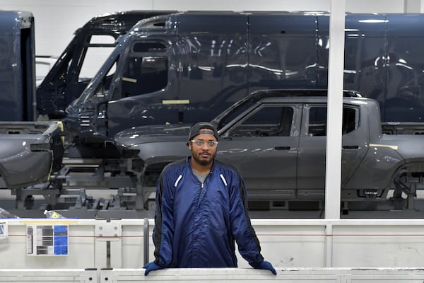 A manufacturing worker stands near the R1T model and the Rivian Amazon EDV 700 van on. The line at Rivian in Normal, Ill., on July 20, 2022. (Photo for the Atlanta Journal Constitution by Ron Johnson)