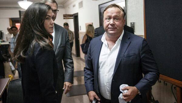 In this Monday, April 17, 2017 photo, "Infowars" host Alex Jones, right, arrives at the Travis County Courthouse in Austin, Texas. Jones, the right-wing radio host and conspiracy theorist, is a performance artist whose true personality is nothing like his on-air persona, according to a lawyer defending the "Infowars" broadcaster in a child custody battle. (Tamir Kalifa/Austin American-Statesman via AP)